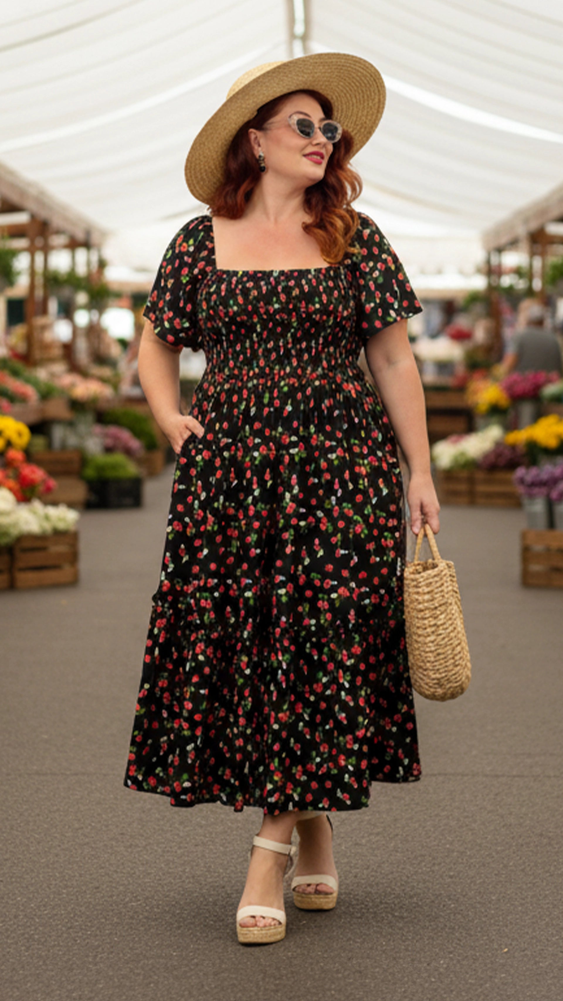 Woman in a floral dress and sun hat at an outdoor market.
