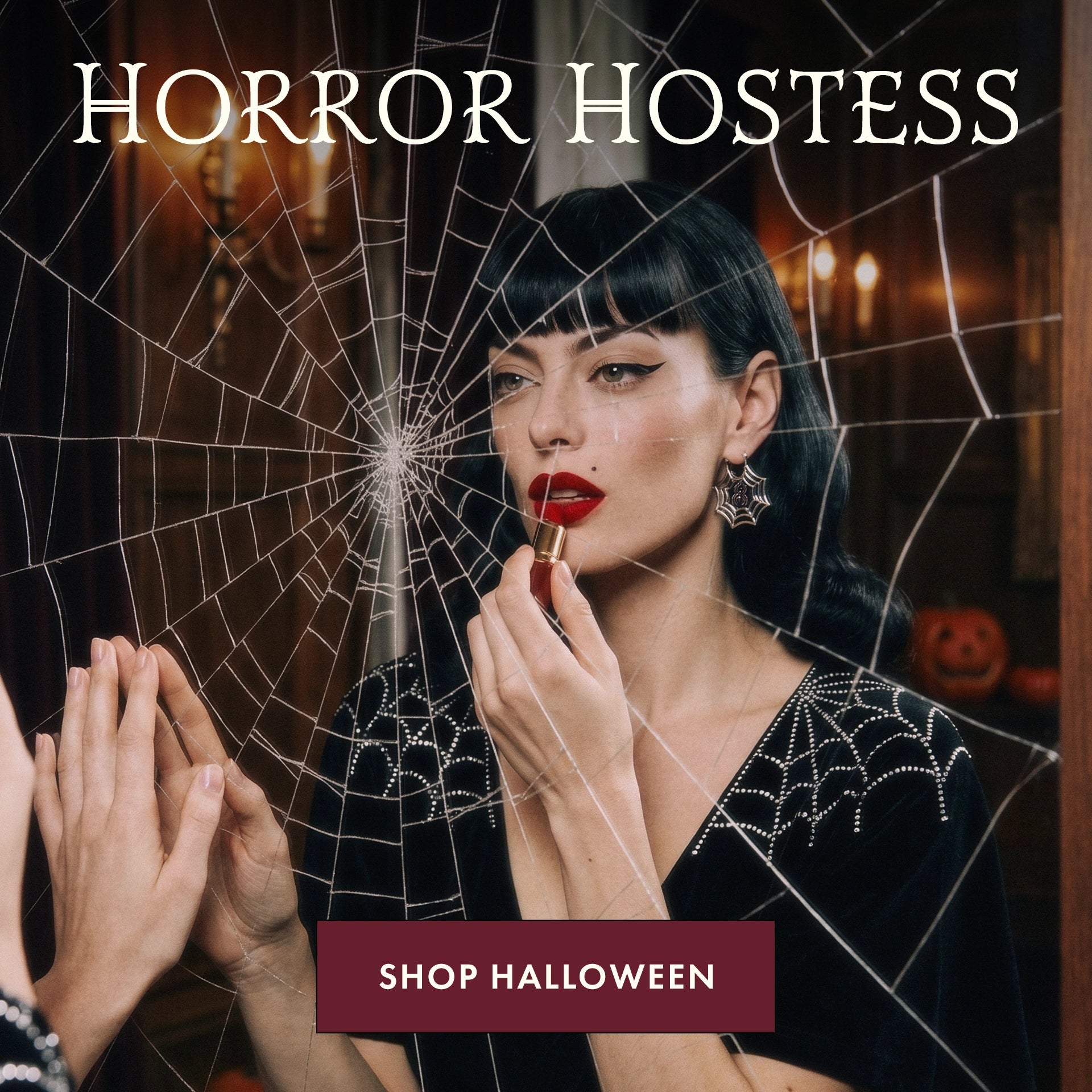 A woman with dark hair and red lipstick applies red lipstick while looking into a mirror covered with a spiderweb overlay. Large text at the top reads 'HORROR HOSTESS' and a maroon banner at the bottom reads 'SHOP HALLOWEEN'.