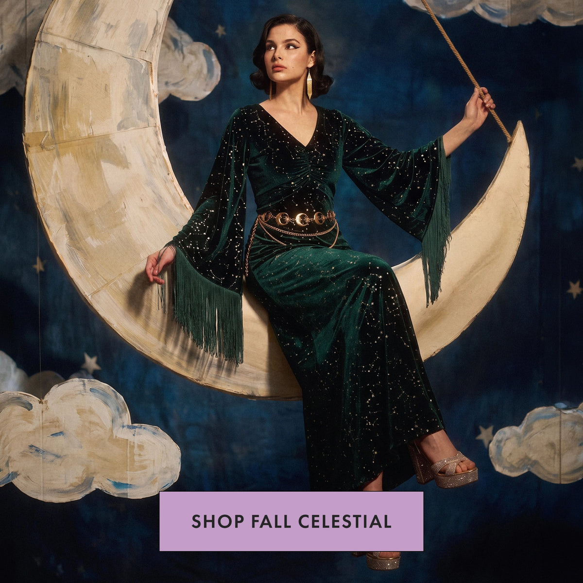 A woman sits on a large crescent moon prop against a dark blue starry backdrop, wearing a deep green velvet gown with fringe sleeves and a gold belt. A purple banner at the bottom reads 'SHOP FALL CELESTIAL'.