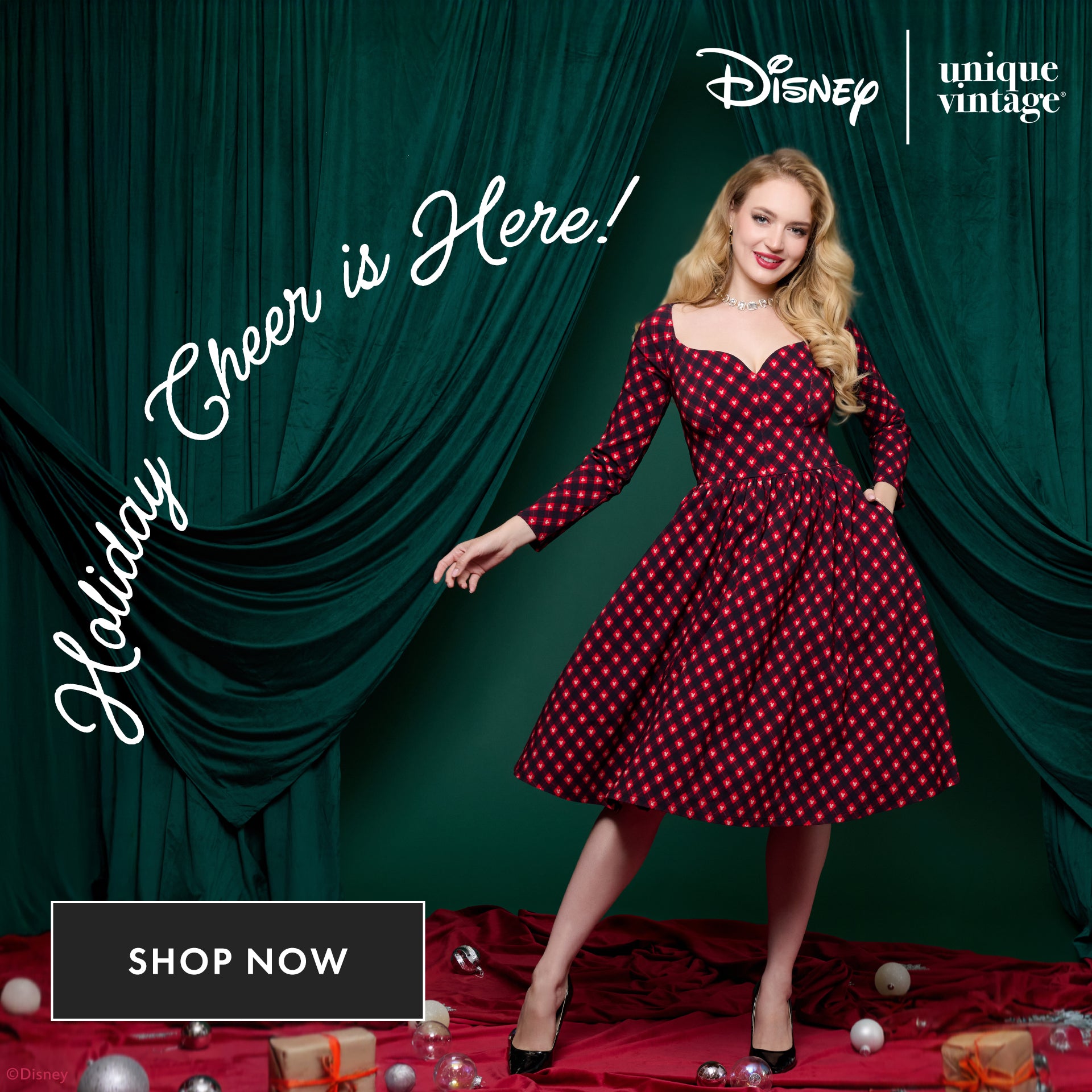 Woman in a red and black polka dot dress standing in front of green curtains with Disney and Unique Vintage logos.