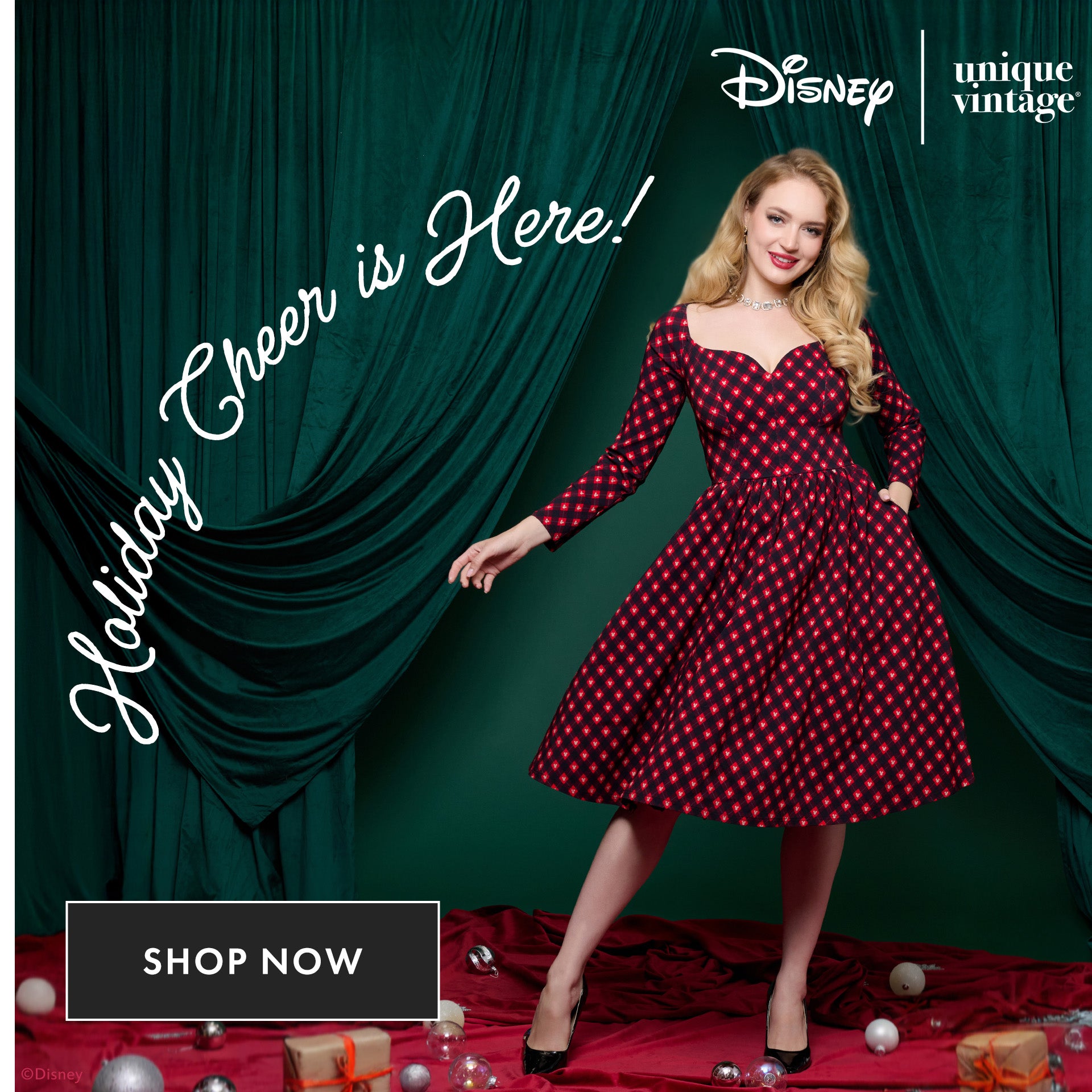 Woman in a red and black polka dot dress standing in front of green curtains with Disney and Unique Vintage logos.
